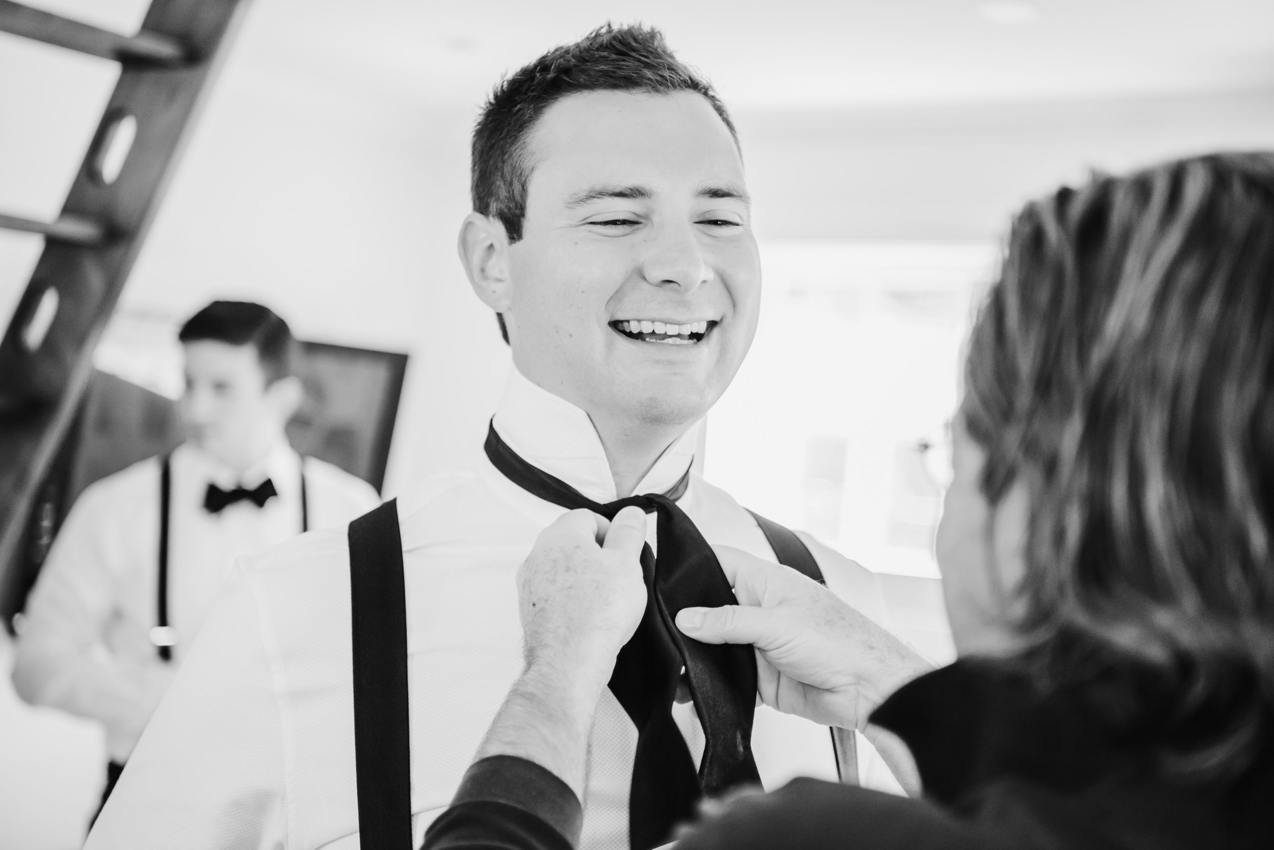Black and white candid photo showing final touches being added to a bowtie.