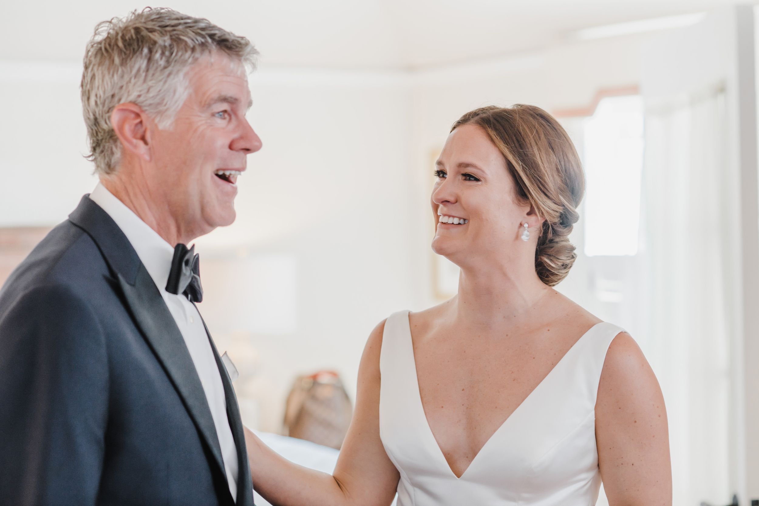 A touching moment captured during wedding preparations in a bright white room.