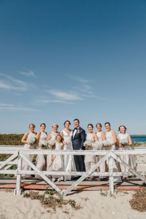 Wedding party members lined up on a wooden boardwalk with ocean views.