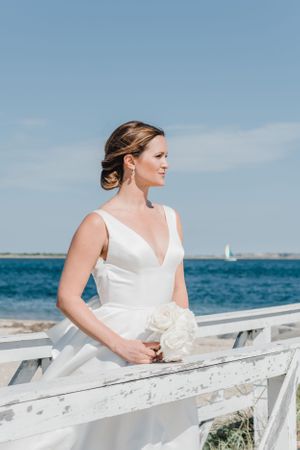 A classic white wedding dress is showcased against the backdrop of blue ocean waters.