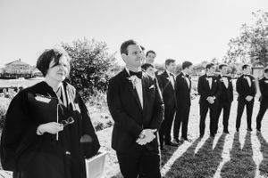 Black and white photo of wedding party lined up outdoors in formal attire.