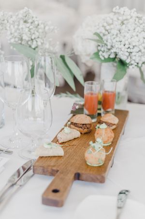 Wedding table setting with appetizers on a wooden board and baby's breath flower arrangements.