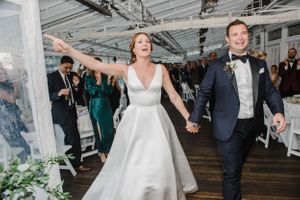 A couple celebrates joyfully during their wedding reception under a clear tent.
