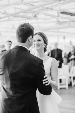 Black and white candid moment during first dance at indoor wedding reception.