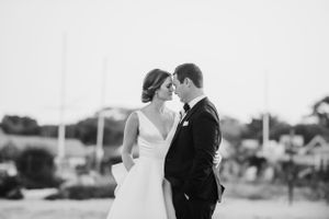 Black and white intimate wedding portrait with coastal scenery in background.
