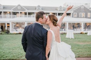 Romantic wedding moment captured on a lawn with coastal buildings in the background.