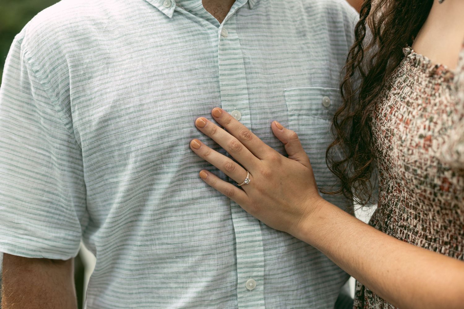 Close-up of hands placed lovingly on a striped shirt during an intimate moment.