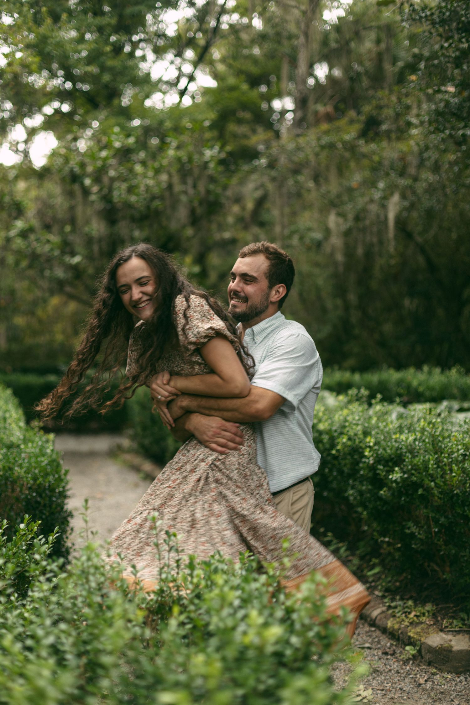 A joyful moment captured as a couple dances and laughs together on a garden path.