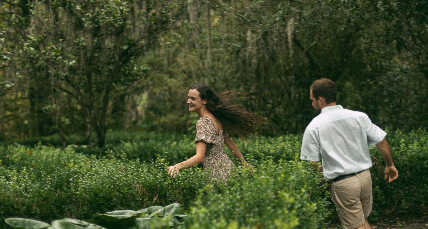 A couple enjoying a playful moment while walking through a garden path.