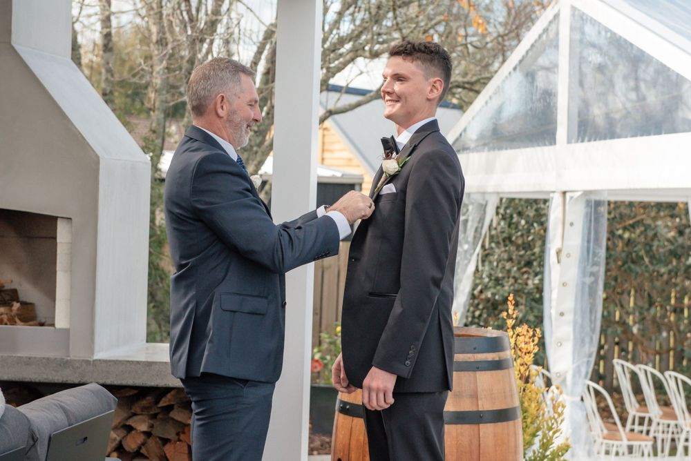 A touching pre-wedding moment between two men in suits adjusting formal attire Cambridge Hamilton New Zealand