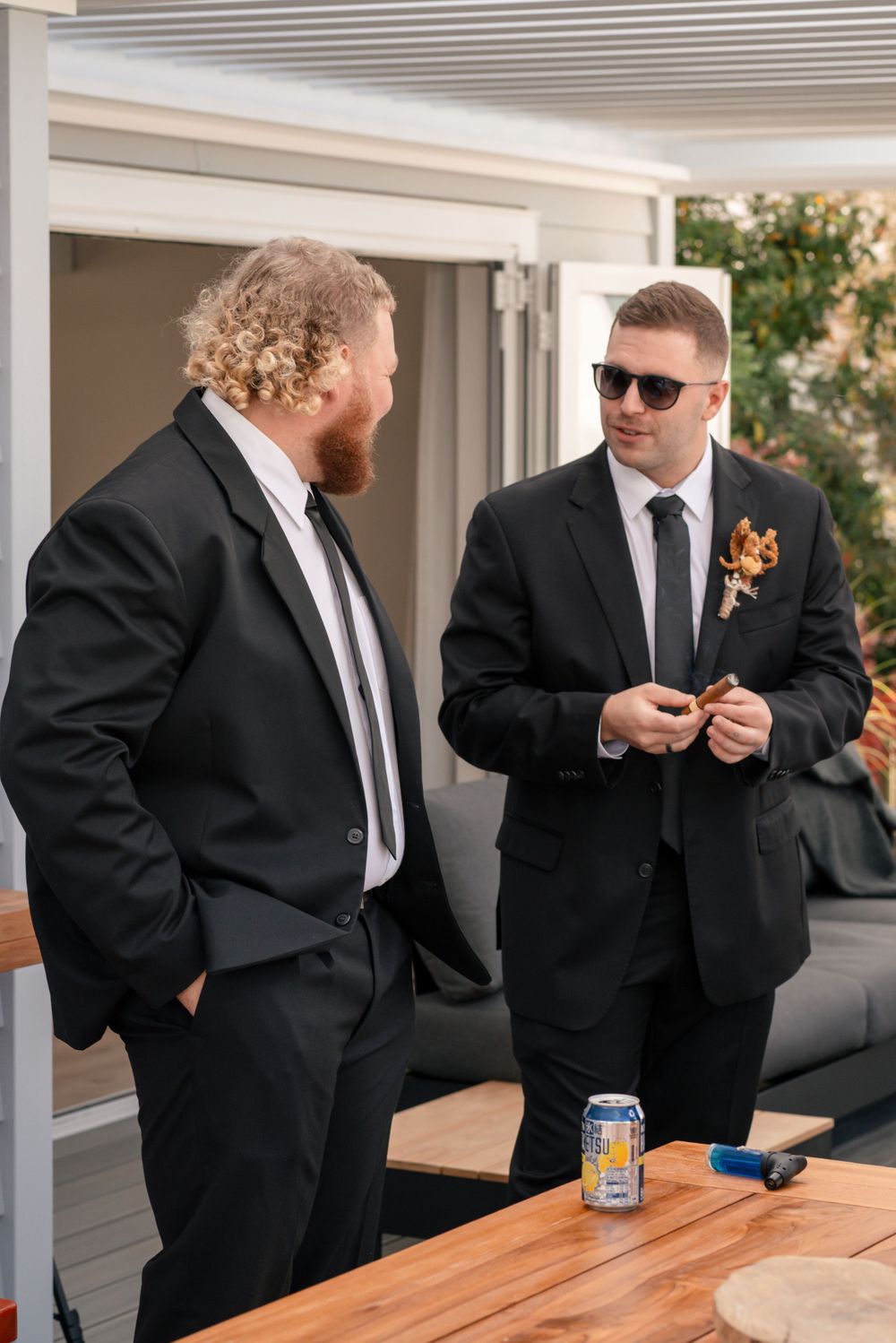 Two men in formal suits chat during wedding preparations on a modern patio Cambridge New Zealand