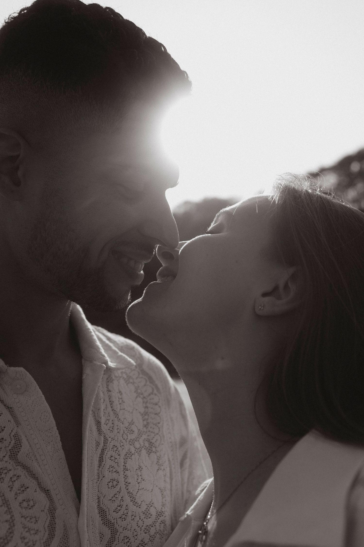 A backlit silhouette portrait of a couple sharing an intimate moment on the beach.