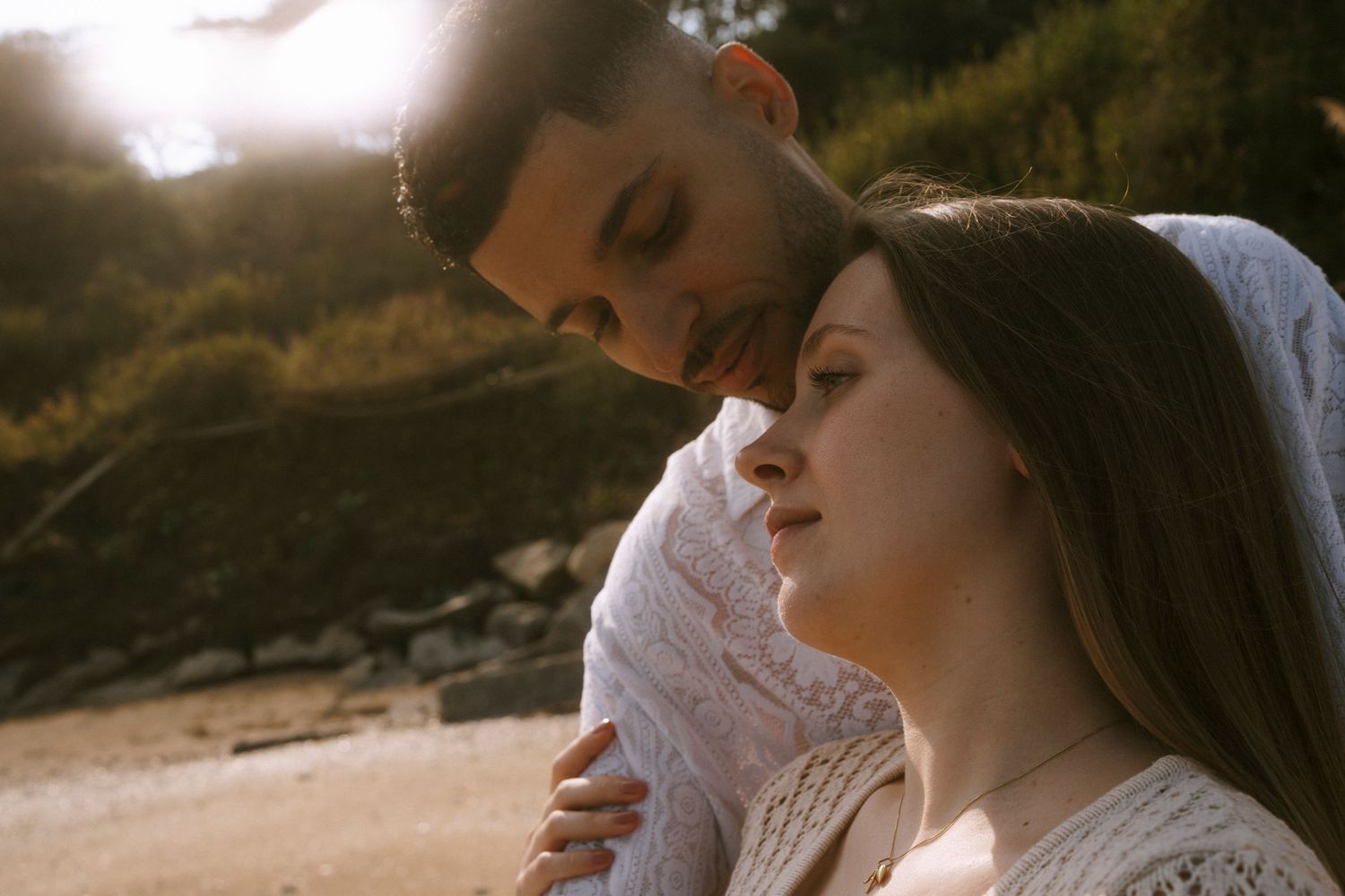 Intimate couple sharing a tender moment in warm sunset light.