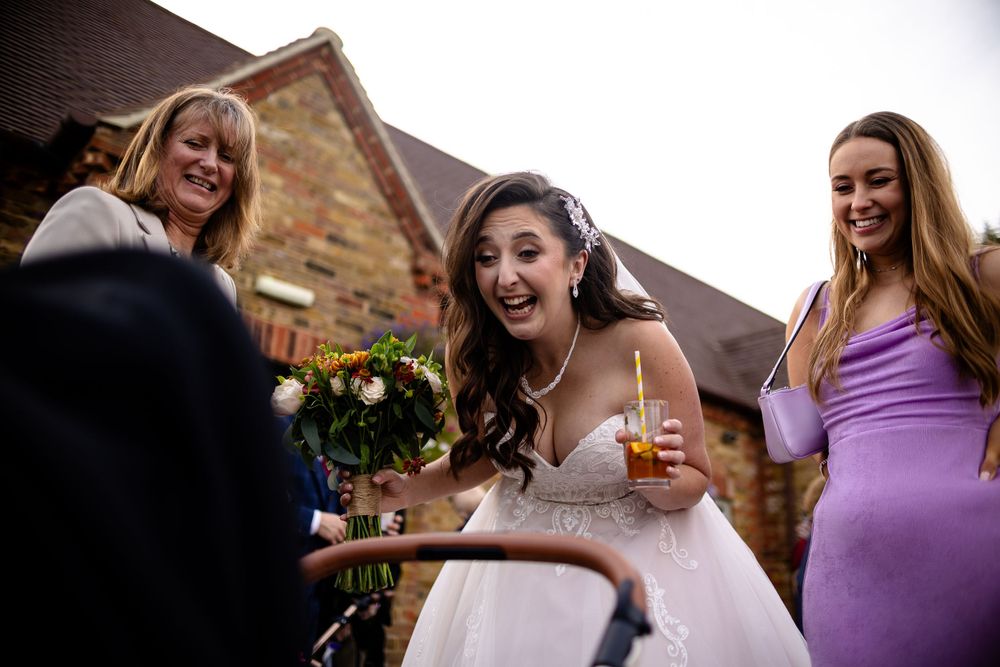 A bride in white dress laughs joyfully while celebrating with wedding guests.