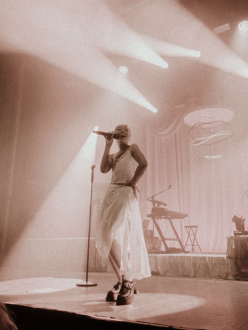 Silhouette of a performer on stage in dramatic sepia lighting.
