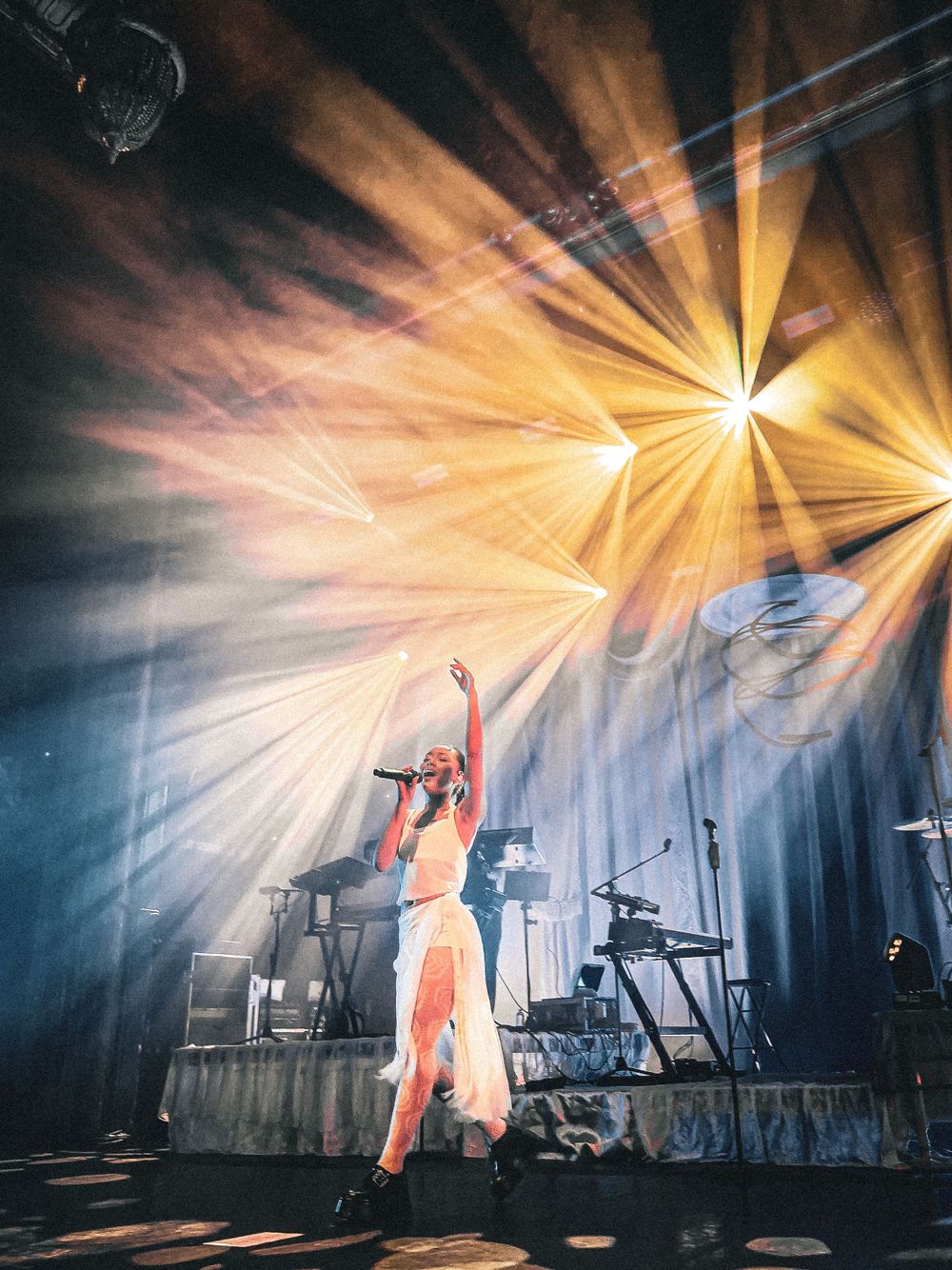 Dramatic orange stage lighting creates sunburst effects during a concert performance.