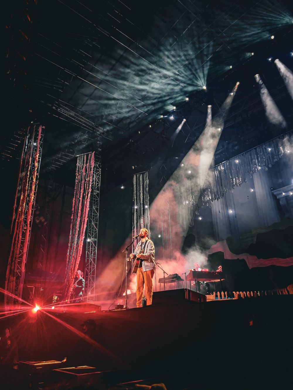 Dramatic concert stage performance with smoke and bright spotlights creating atmospheric lighting effects.
