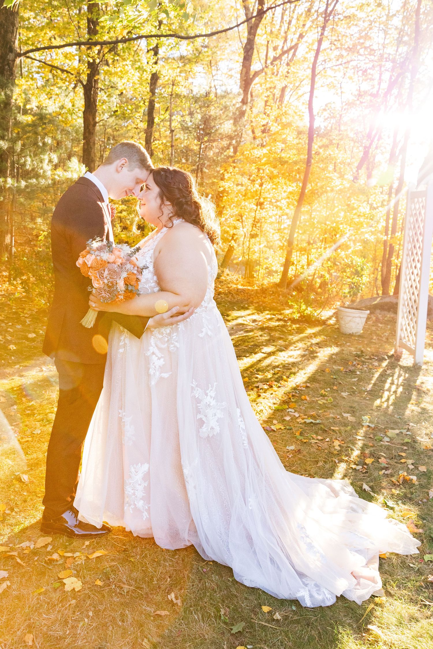 Sunlit autumn wedding portrait with golden light filtering through trees.