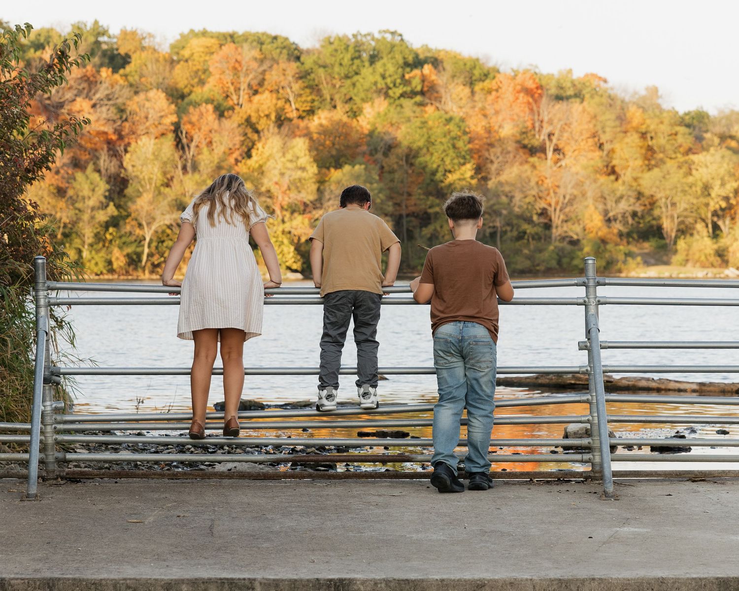 People sitting on a bench overlooking a scenic lake surrounded by fall colors.