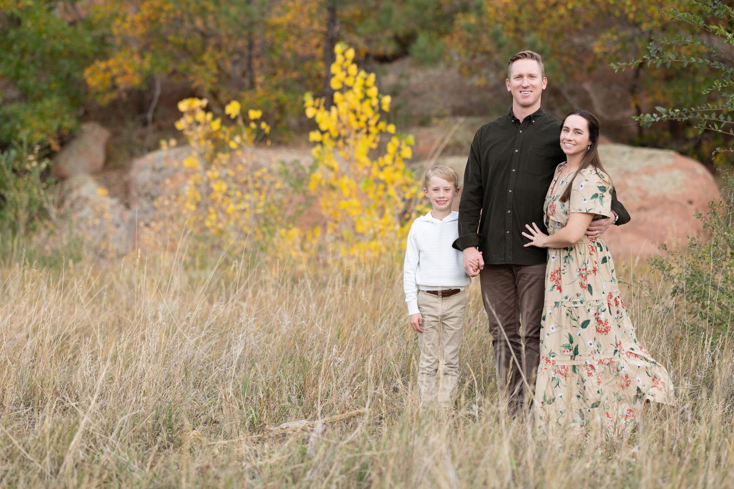 Family portrait in an autumn field with yellow foliage and natural backdrop.