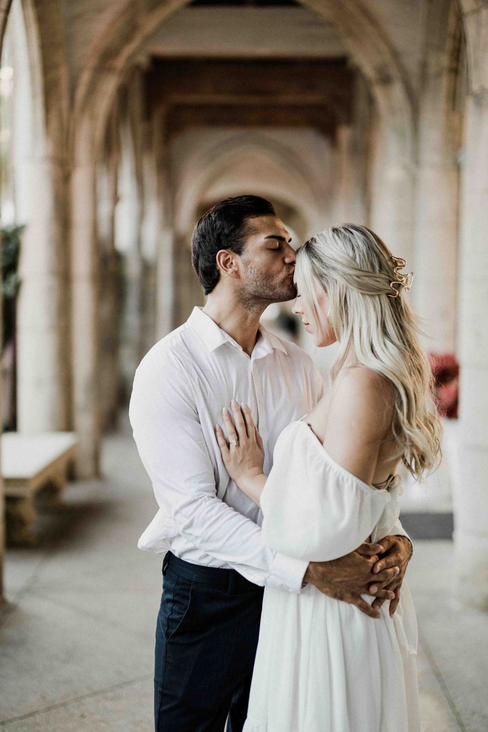 Romantic couple sharing an intimate moment in an elegant arched hallway.