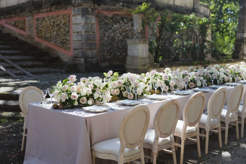 Elegant wedding table setting with white flowers and classic chairs in an outdoor garden.