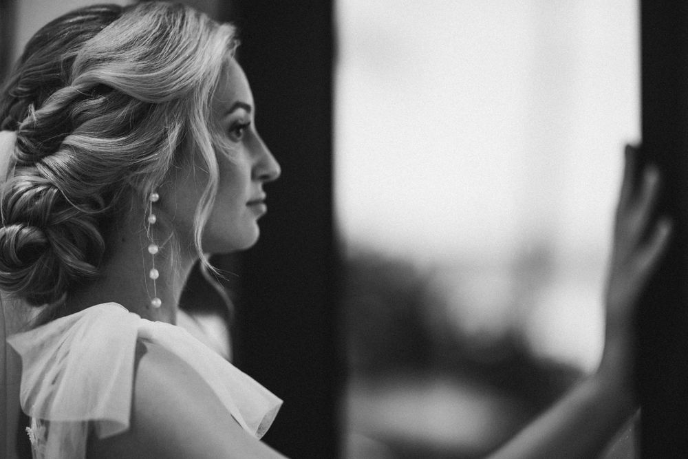 Elegant side profile with vintage-inspired hairstyle and dangling earrings in black and white.