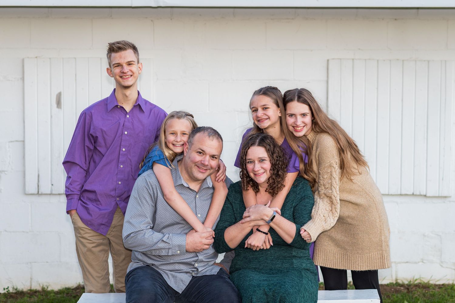 Family group portrait session against white building exterior.