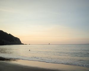 Serene coastal landscape at dawn with gentle waves rolling onto a sandy beach.