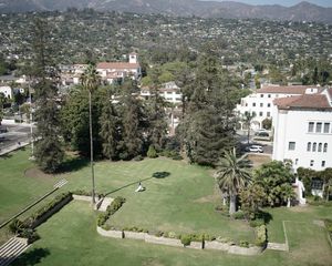 Aerial view of green campus grounds with Spanish architecture and palm trees.