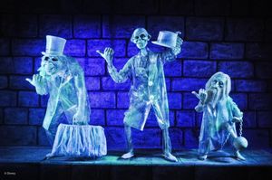 Three ghostly holographic figures in top hats perform as hitchhiking ghosts against a blue-lit brick wall backdrop.