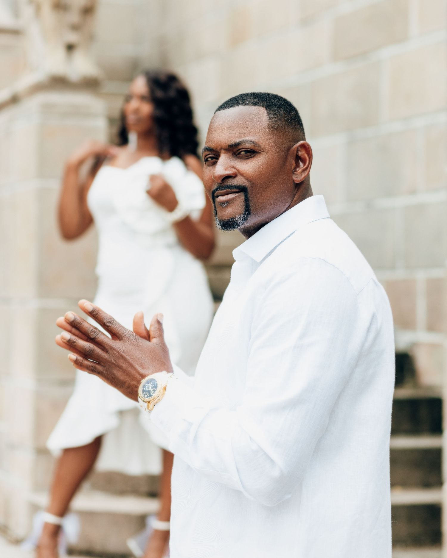 Fashion portrait of a person in a white dress shirt looks sideways with a thoughtful expression while standing outdoors.