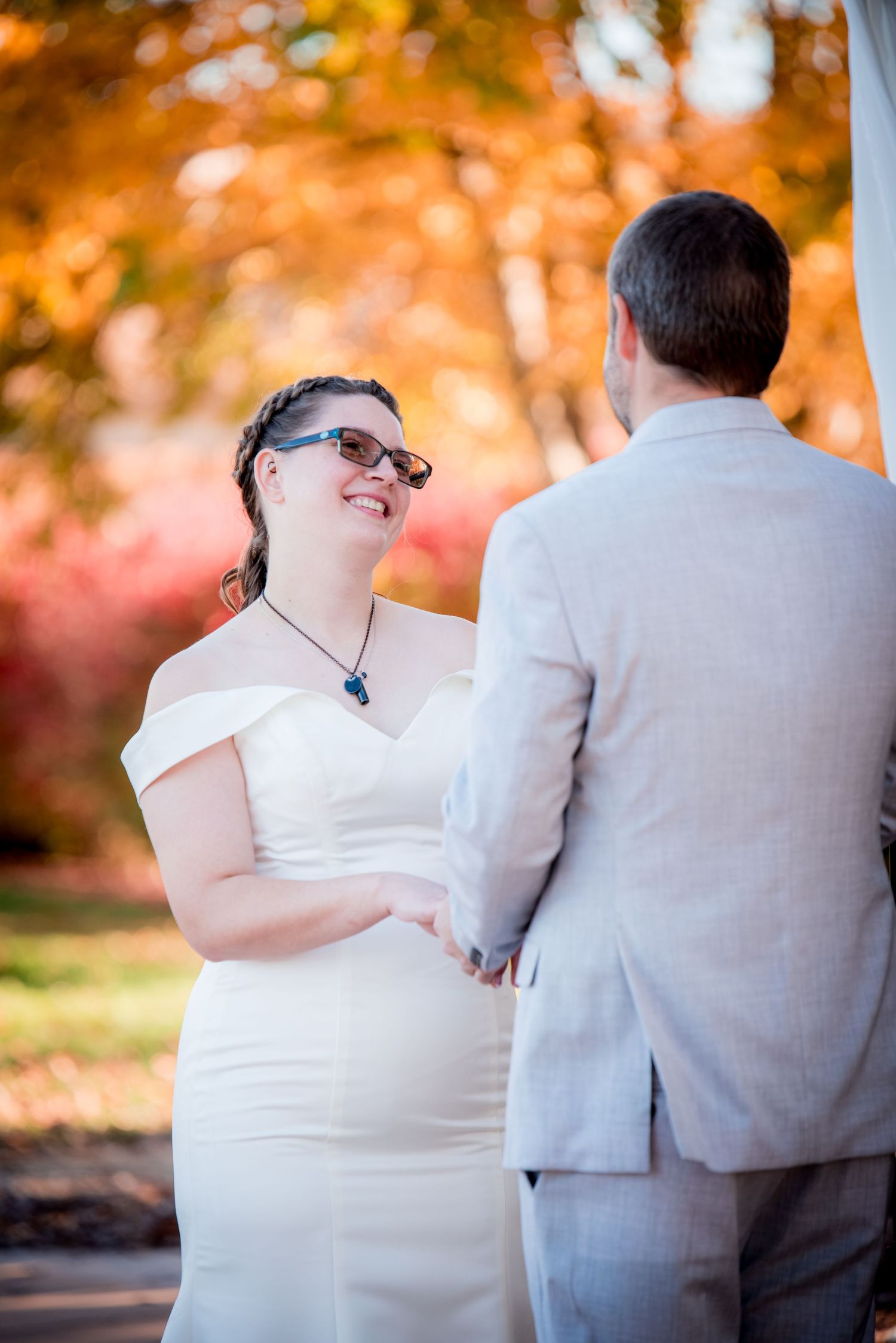 An intimate moment captured during an autumn wedding with vibrant orange foliage in the background.