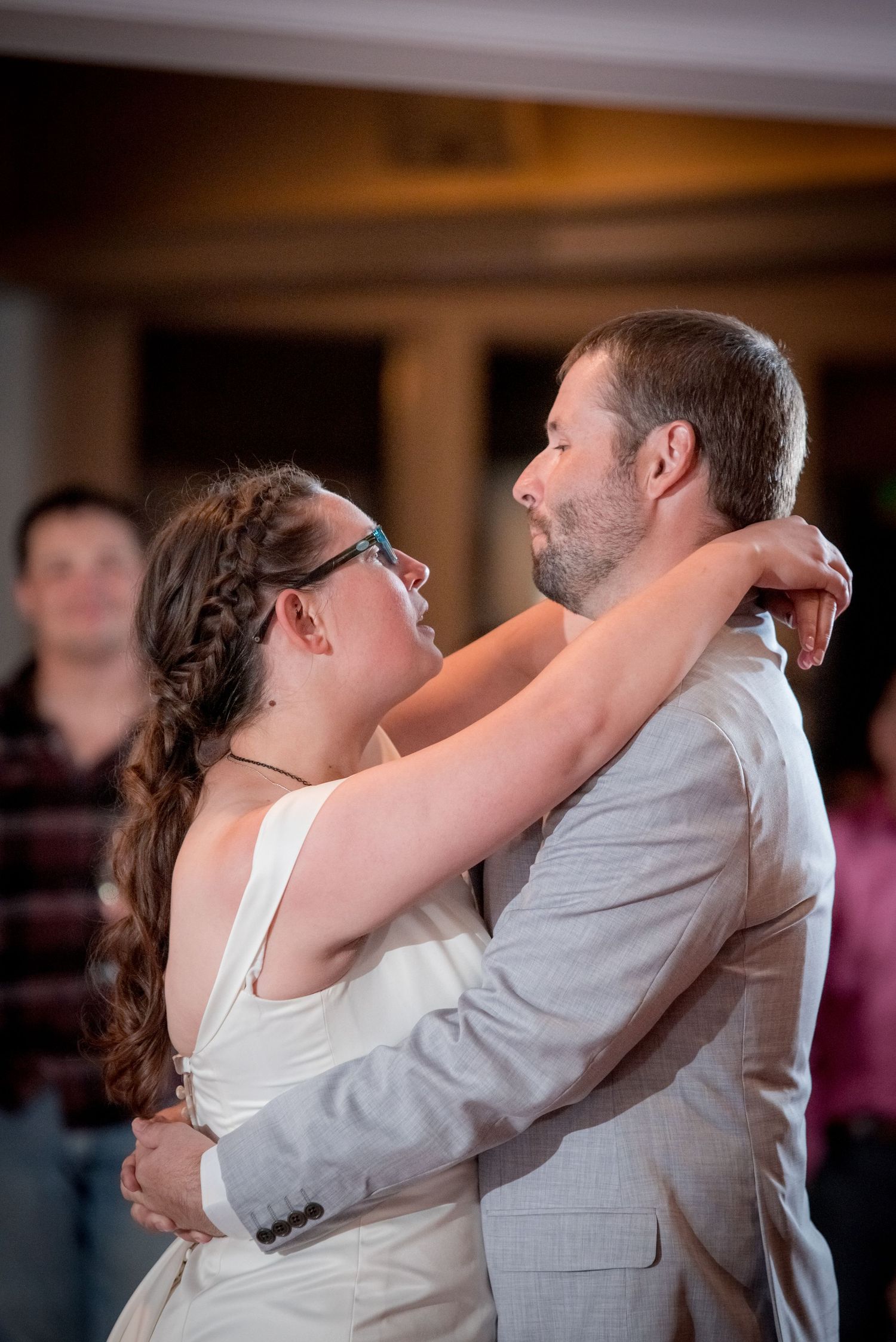 A couple sharing a romantic slow dance together at a wedding reception with soft lighting in the background.