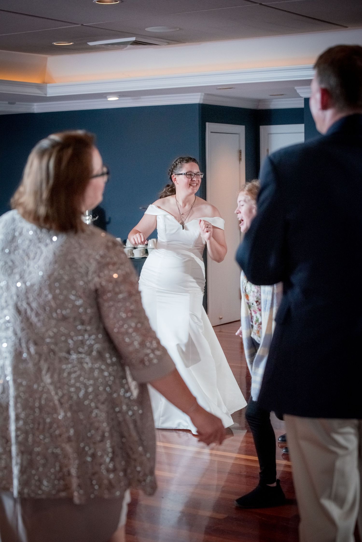 Wedding guests dance and celebrate on a polished hardwood floor in an elegant reception hall.