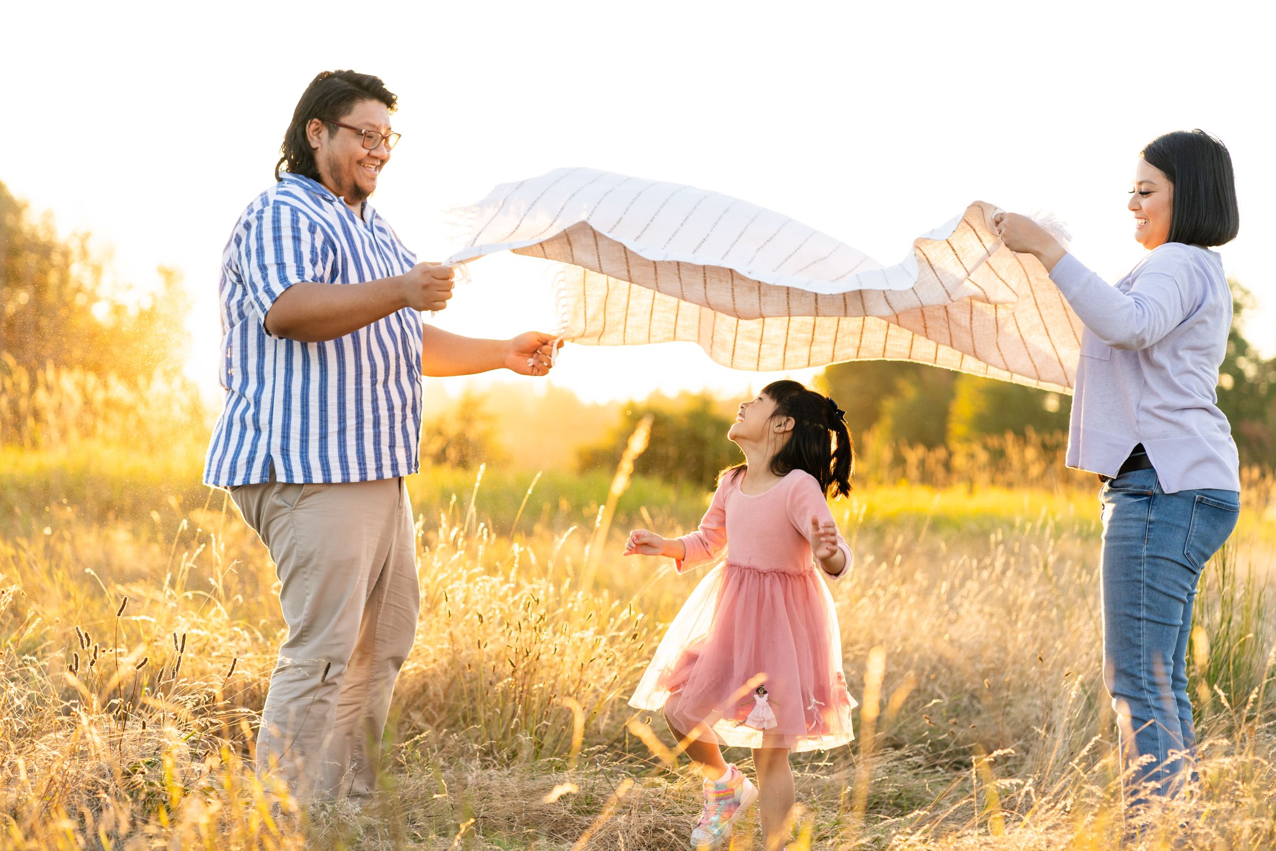 Daughter laughs and runs through a blanket in the air at sunset in Redmond.