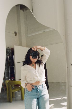 A casual lifestyle portrait in a minimalist interior with an arched doorway featuring a white shirt and light denim jeans.