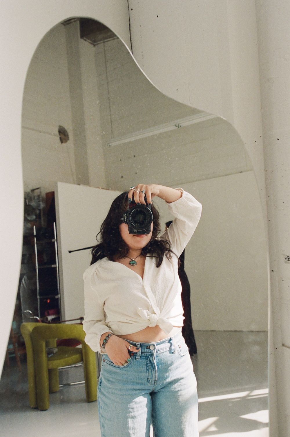 A casual lifestyle portrait in a minimalist interior with an arched doorway featuring a white shirt and light denim jeans.