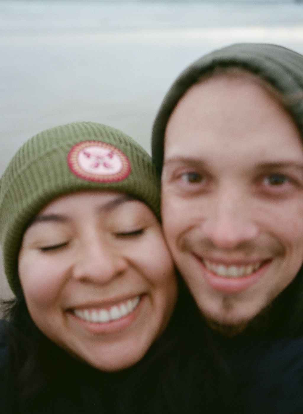 A series of five selfie photos showing a couple wearing green winter hats making playful expressions together.