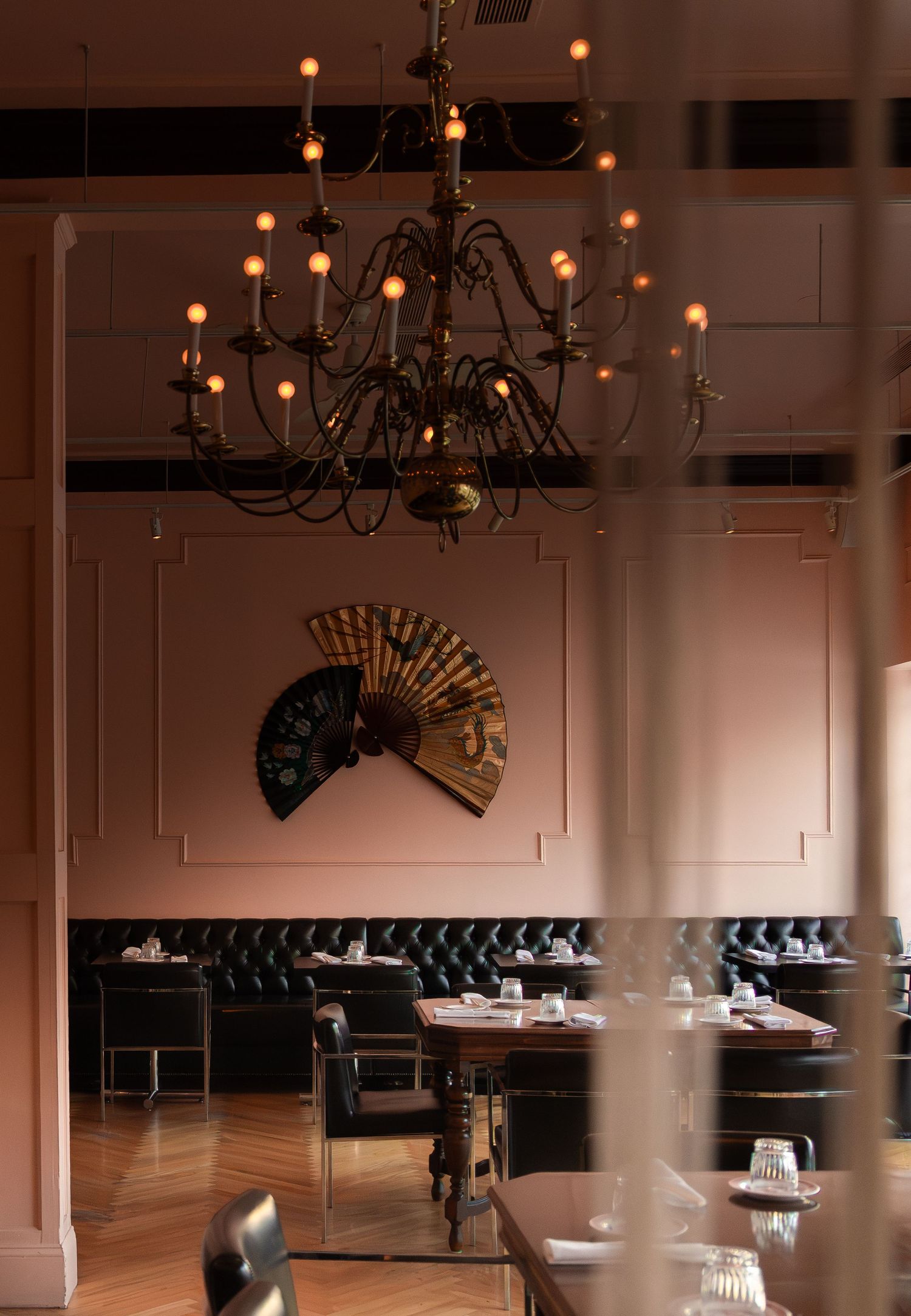 Elegant restaurant interior with chandelier and decorative wall fan in warm lighting.
