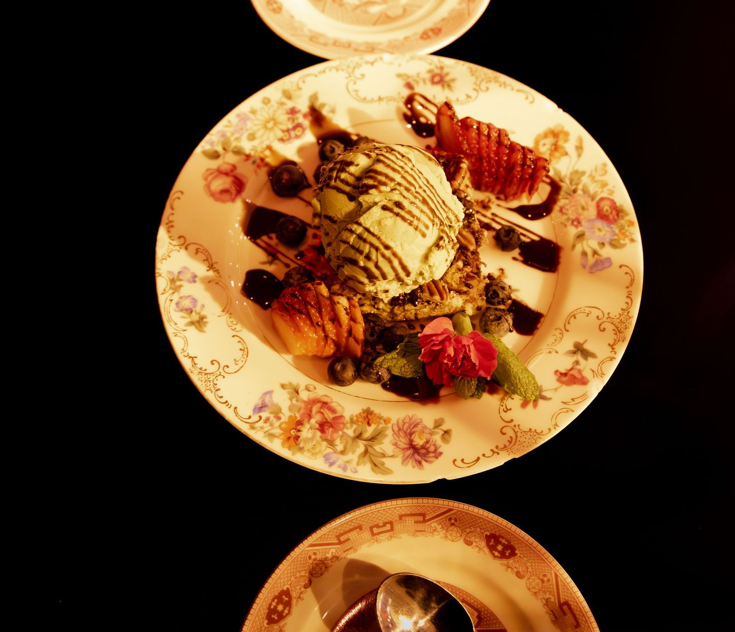 Overhead view of plated dessert with ice cream and berries on floral china.