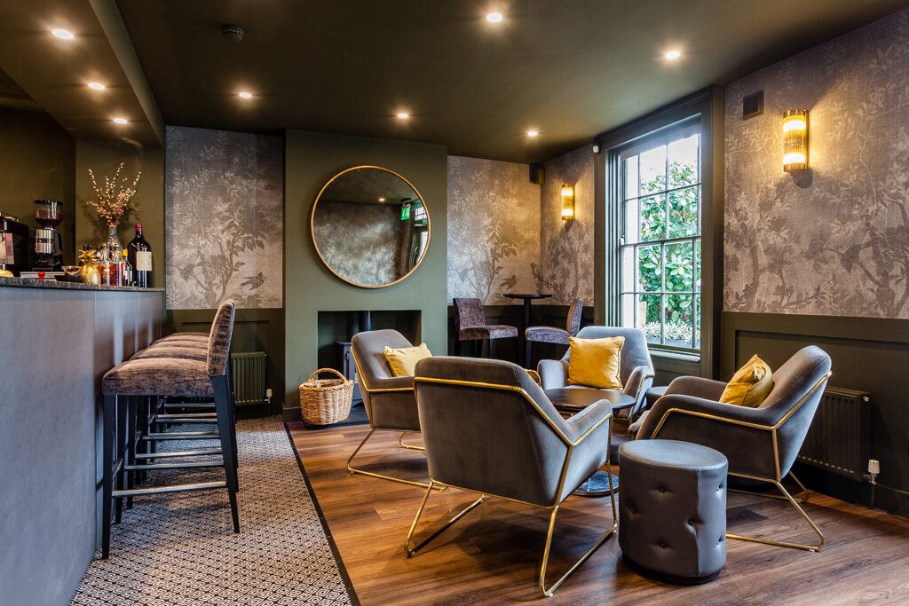 Modern lounge area with plush seating, round mirror, and decorative wallpaper.