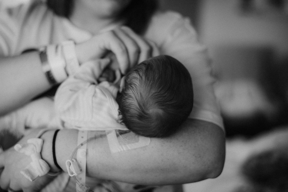 mother holding newborn with IV still in arm captured by Maryland Newborn Photographer Mallory Bramlett.