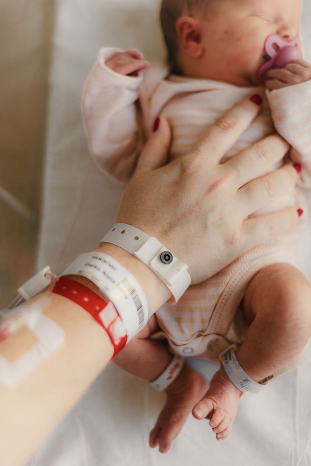 Mother with IV in hand placing hand on newborn captured by Maryland Newborn Photographer Mallory Bramlett.