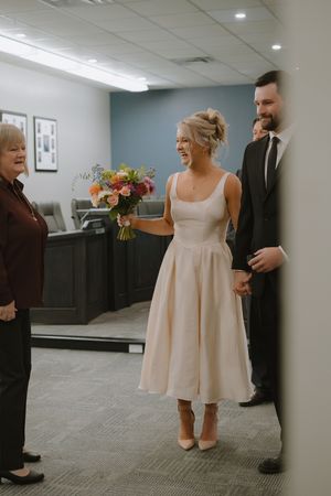 A couple shares a joyful moment at a courthouse wedding ceremony, with the bride wearing a tea-length blush dress.