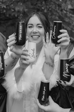 A series of black and white photos showing hands holding black bottles with white feather accents against a dark background.