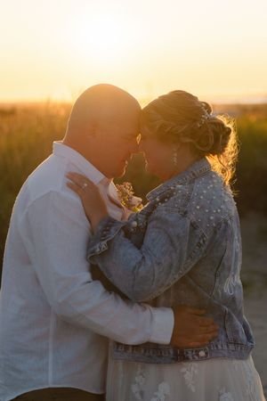 A couple shares an intimate embrace during golden hour sunset in a romantic outdoor setting.