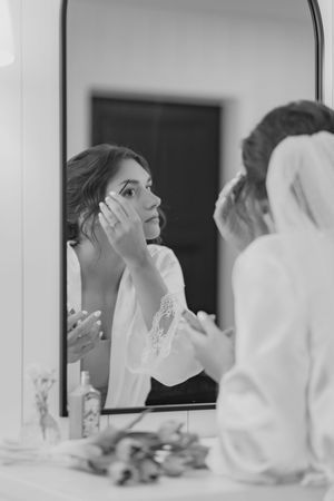 A series of black and white photos showing someone adjusting a bridal veil in front of a mirror.