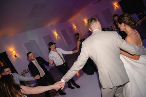 People dancing and celebrating at a wedding reception with warm lighting and a lively dance floor atmosphere.