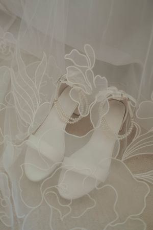 Delicate white lace curtain fabric with floral patterns and embroidered details creates an elegant window covering.